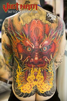 the back of a man's body with tattoos on it and an image of a demon