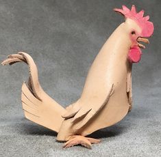 a toy chicken is standing on its hind legs and has a pink comb in it's hair