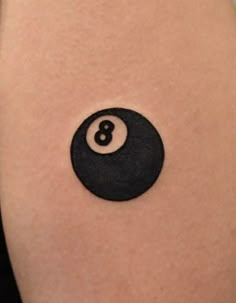 a black eight ball tattoo on the thigh