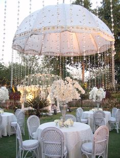 an outdoor dining area with tables, chairs and an umbrella over the table is decorated with white flowers