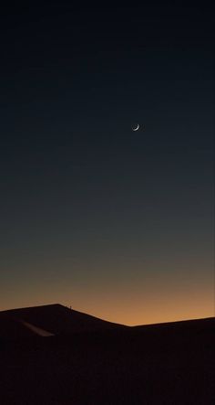 the moon is seen in the sky over a desert landscape at night with no clouds