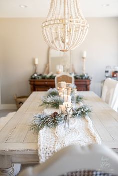 a dining room table decorated for christmas with candles and pine cones on the centerpiece