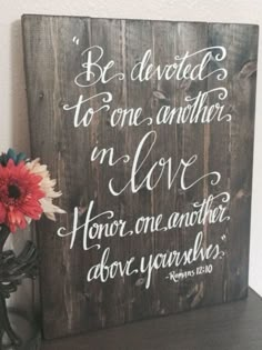 a wooden sign that says be devoted to one another in love