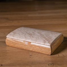 a wooden box sitting on top of a hard wood floor next to a knife blade