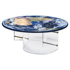 a glass coffee table with the earth on it's side and metal legs, in front of a white background