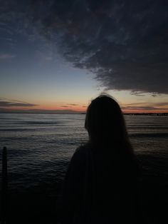 a woman standing on top of a beach next to the ocean at sunset or dawn