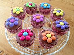 cupcakes with chocolate frosting and colorful candies on top sitting on a wire rack