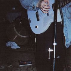 a man holding a guitar while standing in front of a microphone