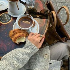 a person is sitting at a table with coffee and croissants on it