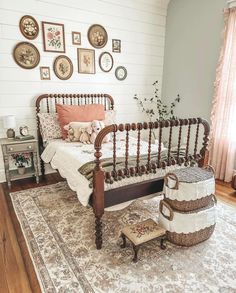 a bed sitting on top of a wooden floor next to a white wall with pictures above it