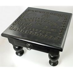 a small black table with carvings on it