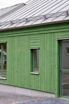 a green building with two windows and a metal roof