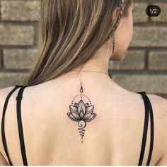 the back of a woman's neck with a lotus tattoo on her left shoulder