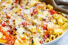 a bowl filled with pasta and cheese on top of a white tablecloth next to a wooden spoon