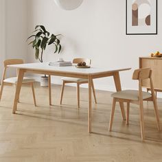 a table and chairs in a room with white walls, wood floors and wooden flooring