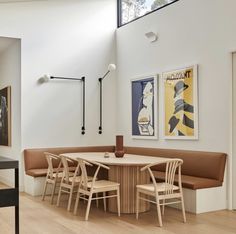 a dining room table with four chairs and a bench in front of the wall that has pictures on it