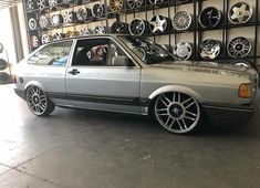 a silver car parked in front of a wall full of rims