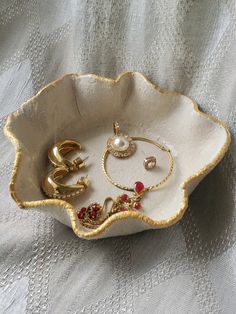 a white bowl filled with lots of jewelry on top of a table