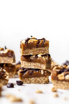 several pieces of chocolate and almond bars stacked on top of each other with nuts scattered around them