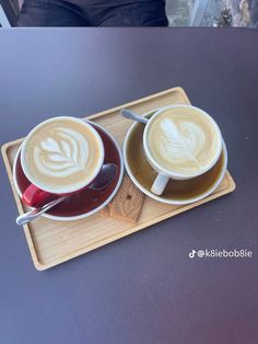 two cups of coffee sitting on top of a wooden tray