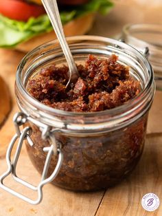 a jar filled with food sitting on top of a cutting board next to hamburgers