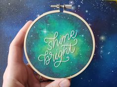 someone is holding up a cross stitch hoop with the words shine bright on it