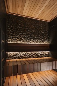 an empty sauna with wood flooring and stone walls