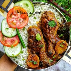 a metal bowl filled with rice, meat and veggies next to cucumbers