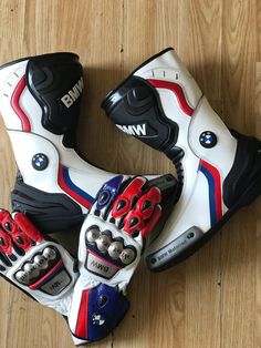 three pairs of motorbike boots sitting on top of a wooden floor