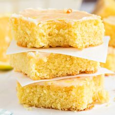 three pieces of cake sitting on top of each other with frosting and lemons in the background