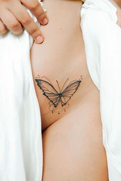 a woman's stomach with a butterfly tattoo on her belly and the bottom part of her breast