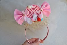 a person is holding up a pink and white headband with candy lollipops on it