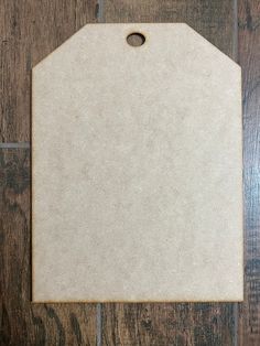 a white cutting board on top of a wooden floor with a tag attached to it