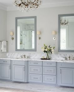 a bathroom with two sinks, mirrors and a chandelier