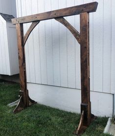 a wooden structure sitting in the grass next to a building