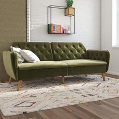 a green couch sitting on top of a wooden floor next to a white brick wall