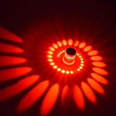 a red light is shining in the dark with its reflection on the wall and it's circular shape