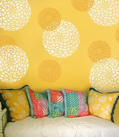 a couch sitting in front of a yellow wall with decorative circles on it's side