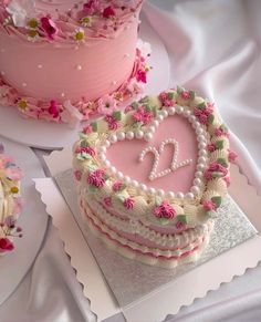 a heart shaped cake sitting on top of a table next to other cakes and cupcakes