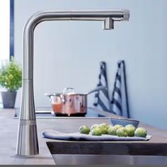 a kitchen faucet that is on top of a counter next to some vegetables