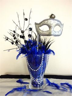 a blue vase filled with feathers and a mask