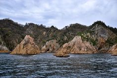 some very pretty rocks in the middle of the water with trees on top of them