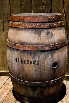 an old wooden barrel sitting on top of a wooden floor next to a fence and door