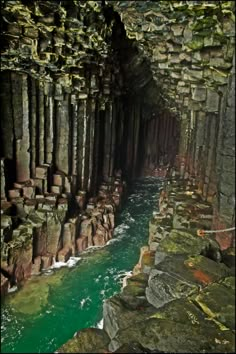 the inside of a cave with green water and rocks on either side, looking down at it