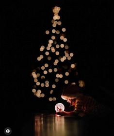 a young child is playing with a light ball in front of a lit christmas tree