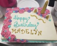 a birthday cake decorated with pink roses and an unicorn horn on the top that says happy birthday madelyn