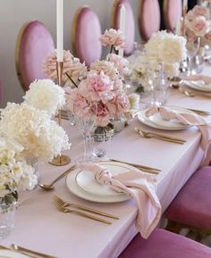 the table is set with pink and white flowers in vases, silverware, and candlesticks