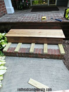 a wooden bench sitting on top of a brick walkway next to a flower potted planter