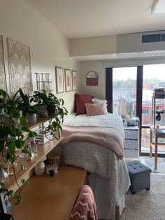 a bed room with a neatly made bed next to a sliding glass door and potted plants