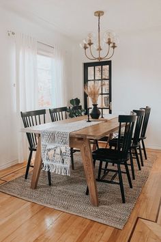 a dining room table with black chairs and a chandelier